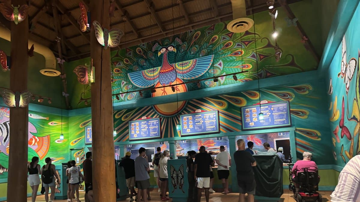 The colorful, art-covered interior of Pizzafari at Disney's Animal Kingdom — a quick-service pizza restaurant on Discovery Island featuring vibrant animal-themed murals lining every wall and ceiling.